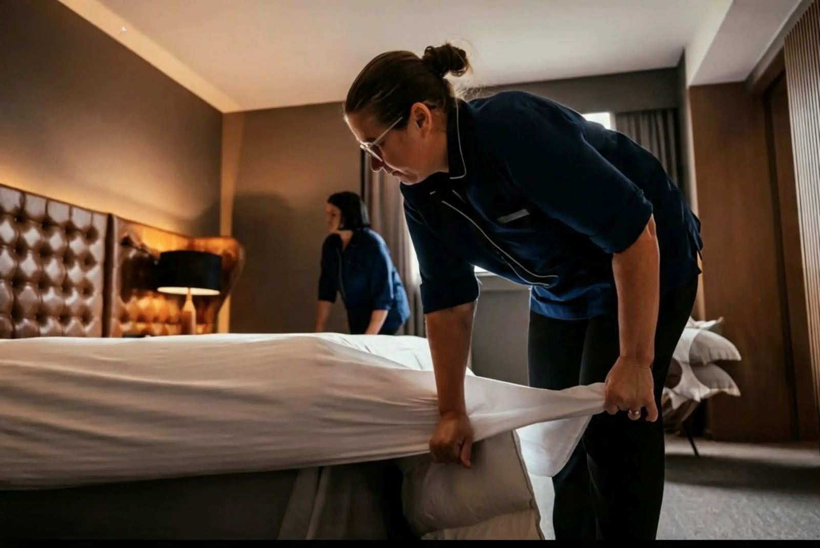 Une collaboratrice Nitida refait un lit dans une chambre d’hôtel